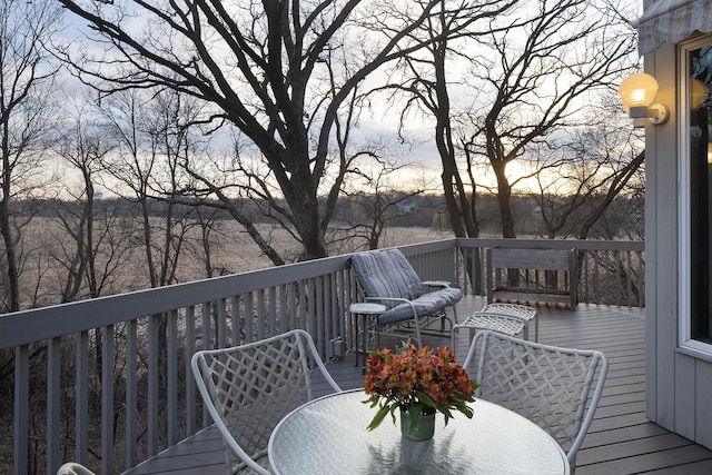 deck at dusk featuring outdoor dining space