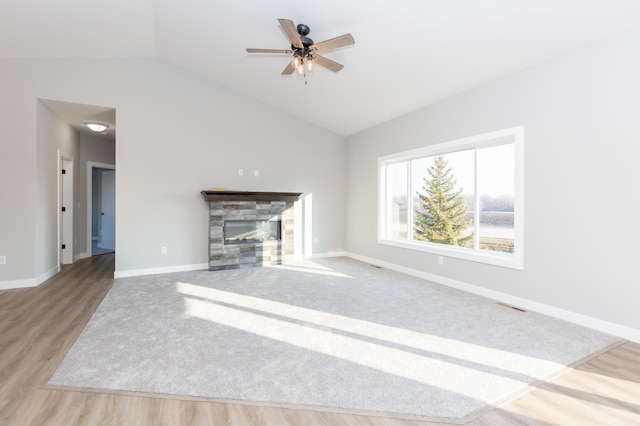 unfurnished living room with lofted ceiling, a fireplace, ceiling fan, and light wood-type flooring