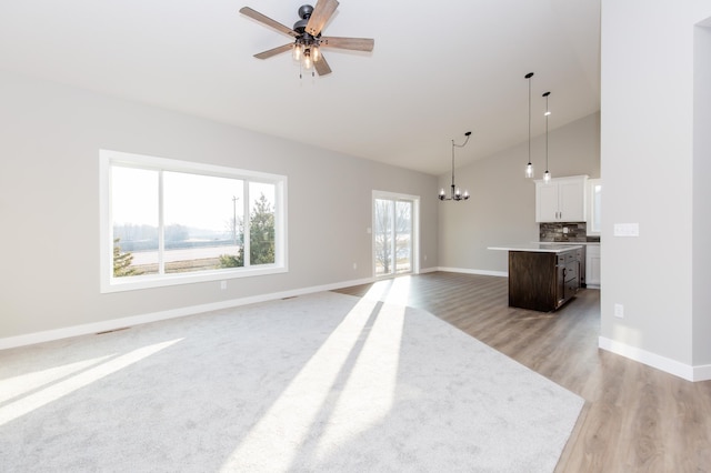 living room with high vaulted ceiling, light hardwood / wood-style floors, and ceiling fan with notable chandelier