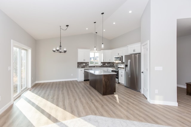 kitchen with a kitchen island, white cabinetry, appliances with stainless steel finishes, and hanging light fixtures