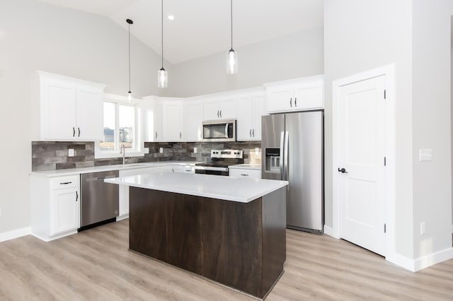 kitchen with stainless steel appliances, white cabinetry, a center island, and decorative light fixtures