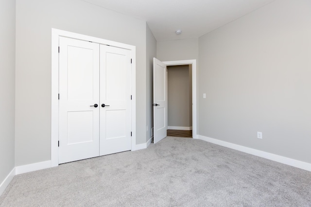 unfurnished bedroom with light carpet and a closet