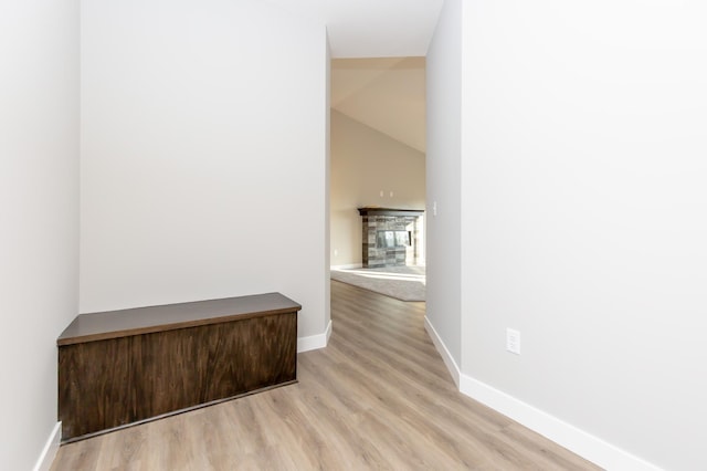 corridor with vaulted ceiling and light hardwood / wood-style flooring