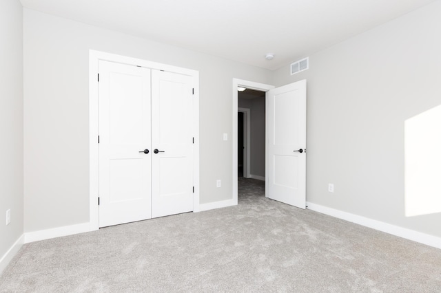 unfurnished bedroom featuring a closet and light carpet