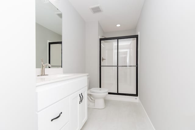 bathroom featuring vanity, a shower with shower door, and toilet