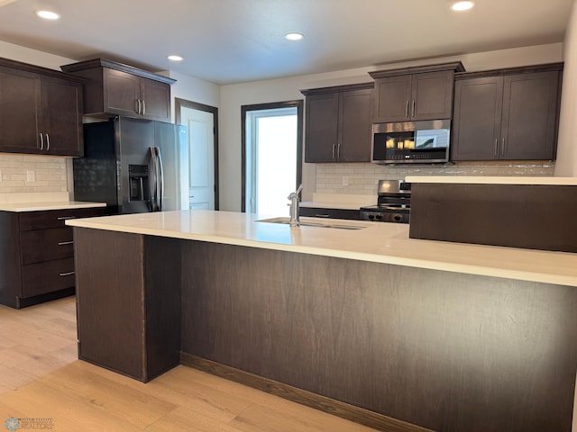 kitchen with dark brown cabinetry, sink, stainless steel appliances, and light hardwood / wood-style floors