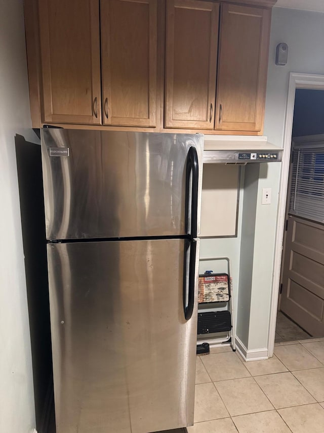 kitchen with light tile patterned flooring and freestanding refrigerator