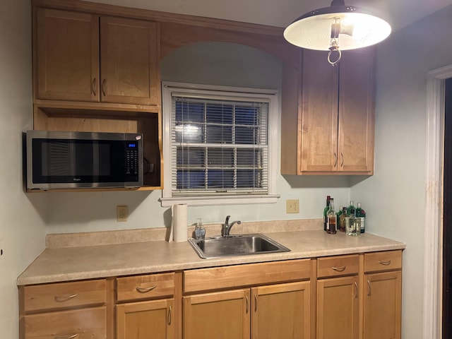 kitchen with stainless steel microwave, light countertops, and a sink