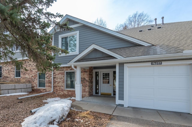 view of front of house featuring a garage, brick siding, and roof with shingles