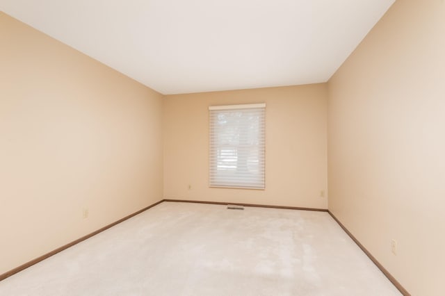 spare room featuring light carpet, visible vents, and baseboards