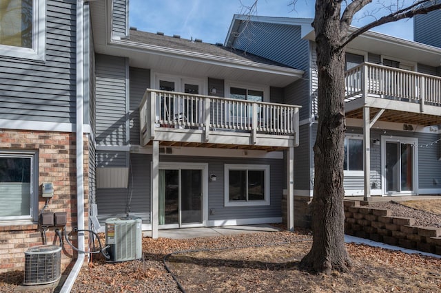 rear view of property featuring brick siding and central AC