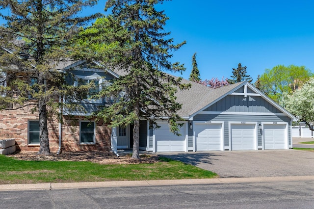 6964 Langford Ct, Edina, MN 55436 - view of front of house featuring board and batten siding, driveway, an attached garage, brick siding, and roof with shingles