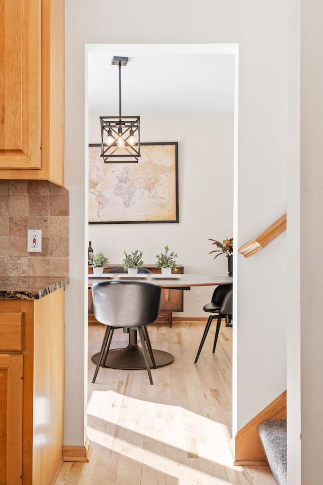 dining area with light wood-style flooring, stairway, and baseboards