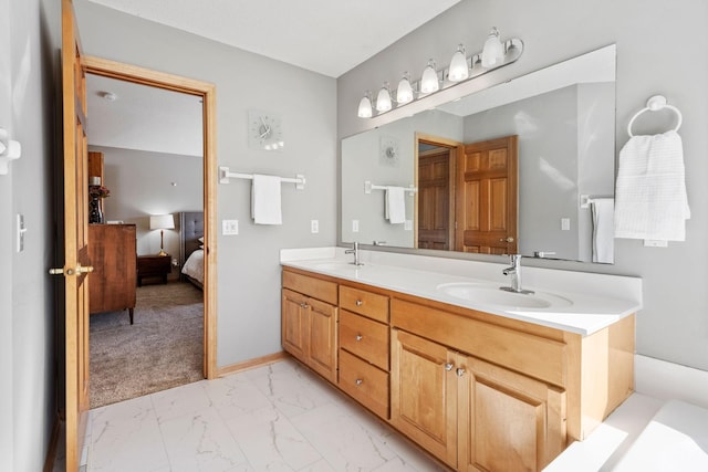 bathroom featuring marble finish floor, double vanity, ensuite bath, and a sink