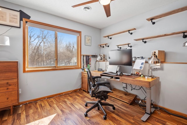 home office with visible vents, a ceiling fan, a textured ceiling, light wood-type flooring, and baseboards