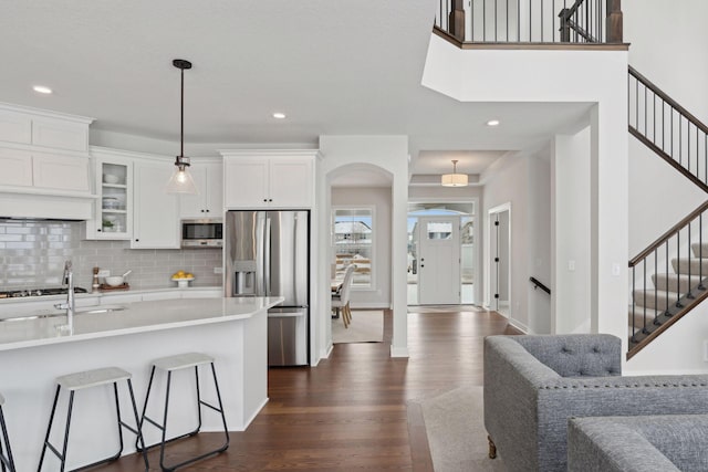 kitchen featuring decorative light fixtures, white cabinets, dark hardwood / wood-style flooring, a kitchen bar, and stainless steel appliances