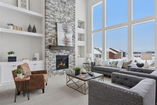 living room with a high ceiling, light carpet, built in features, and a fireplace