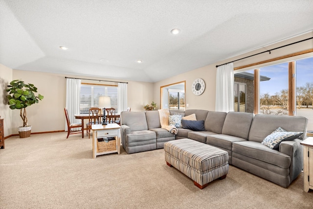 carpeted living room featuring vaulted ceiling, a textured ceiling, and a wealth of natural light