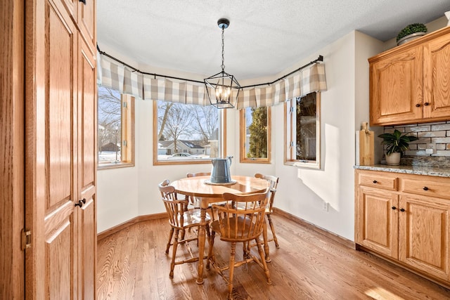 dining space with light hardwood / wood-style floors, an inviting chandelier, and a textured ceiling