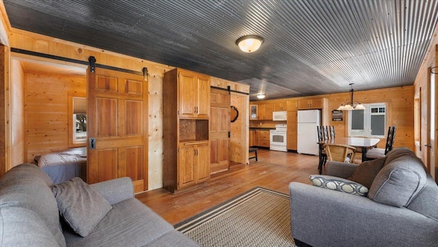 living room with light wood-type flooring, wood ceiling, wood walls, and a barn door