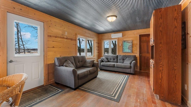 living area with wood finished floors, wood walls, and a wall mounted AC