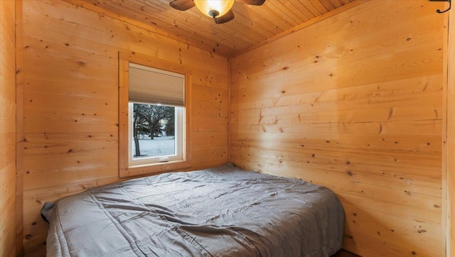 bedroom with ceiling fan, wooden ceiling, and wooden walls