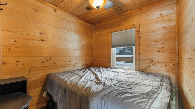 bedroom featuring wood walls, wooden ceiling, and a ceiling fan