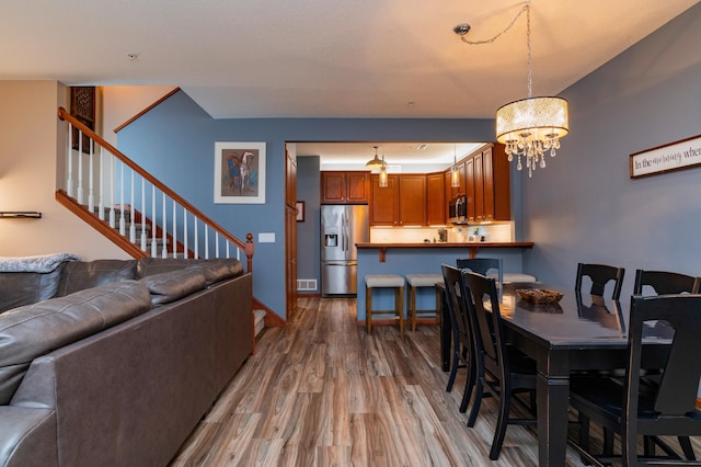 dining room with a notable chandelier, stairs, baseboards, and wood finished floors