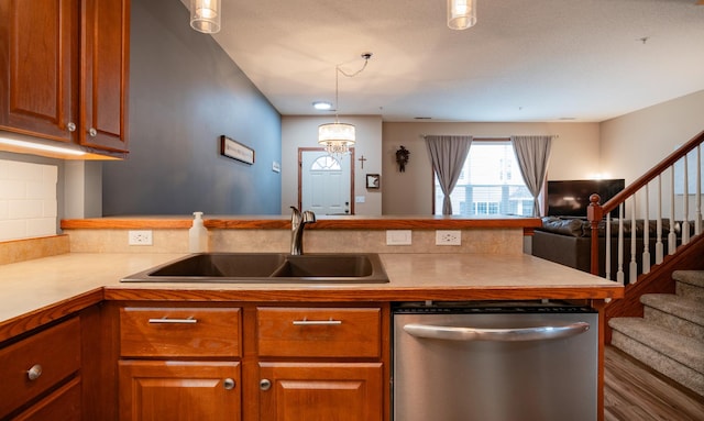 kitchen with brown cabinets, open floor plan, a sink, dishwasher, and a peninsula