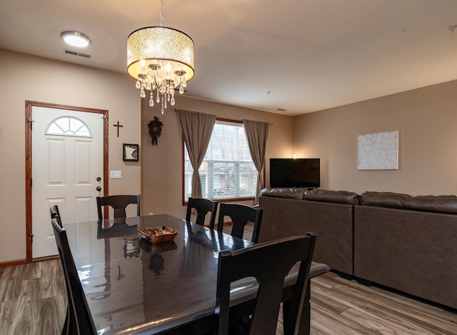 dining room with an inviting chandelier, visible vents, and light wood finished floors