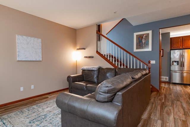 living area with stairway, visible vents, baseboards, and wood finished floors