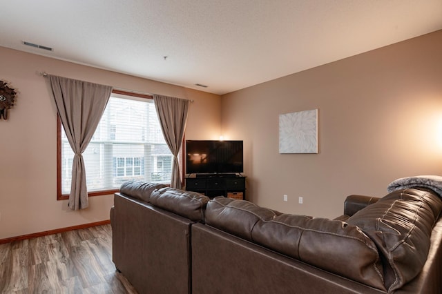 living room featuring visible vents, baseboards, and wood finished floors