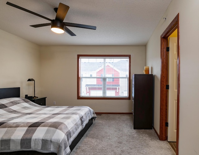 bedroom with a ceiling fan, light colored carpet, a textured ceiling, and baseboards