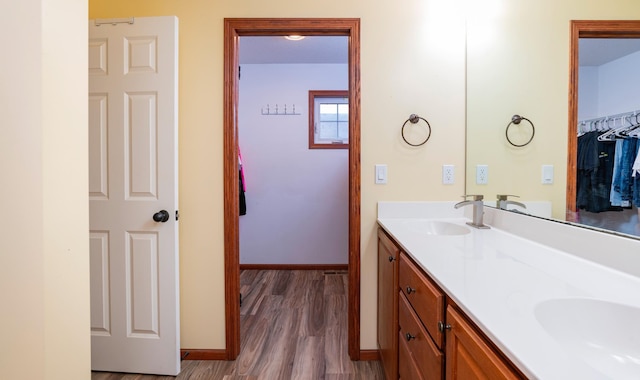 bathroom with double vanity, baseboards, a sink, and wood finished floors