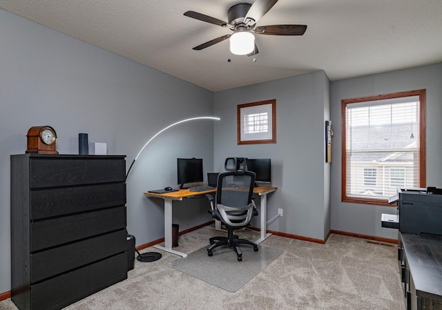 carpeted office space with a ceiling fan and baseboards