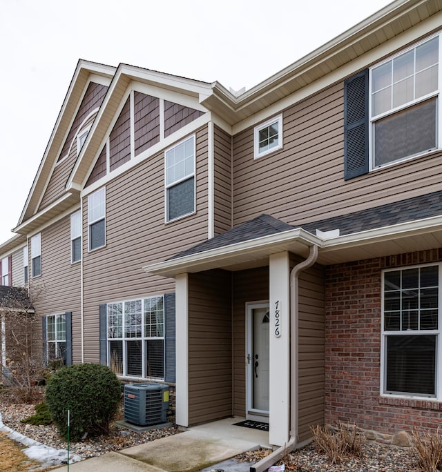 view of front of home featuring cooling unit and brick siding