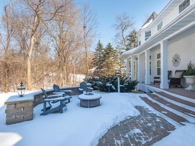 yard covered in snow with a porch and a fire pit