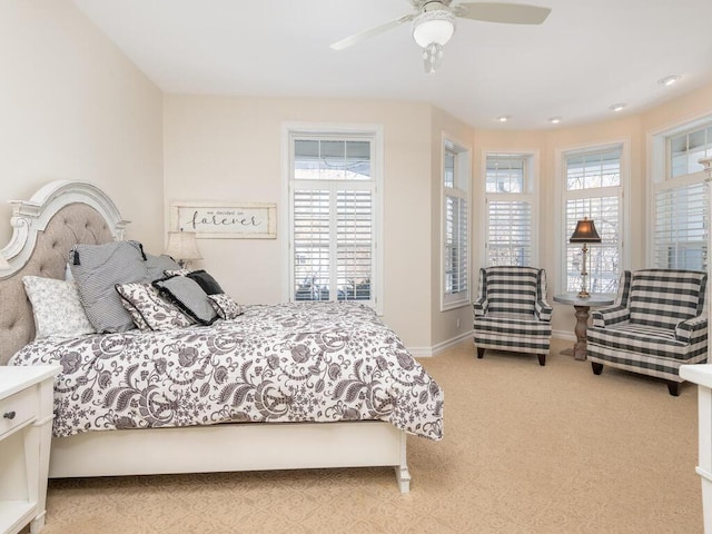 bedroom featuring baseboards, multiple windows, a ceiling fan, and light colored carpet