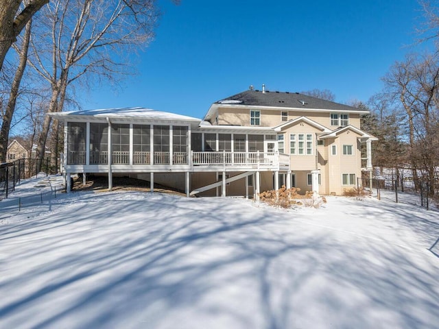 snow covered back of property with a sunroom