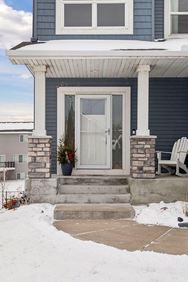 snow covered property entrance featuring covered porch