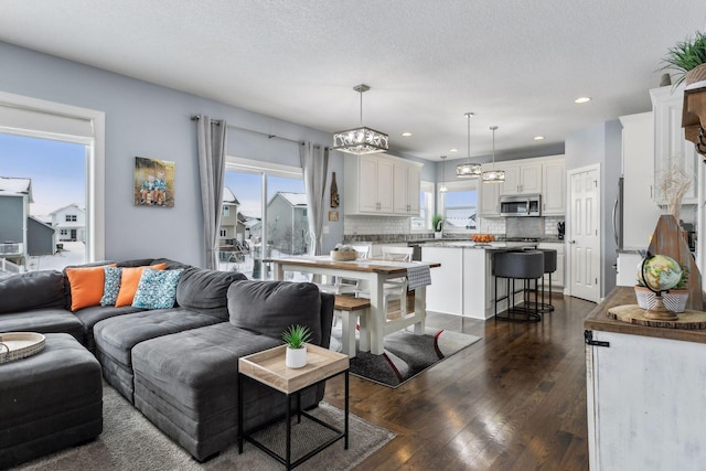 living room featuring a textured ceiling, dark wood-type flooring, and plenty of natural light