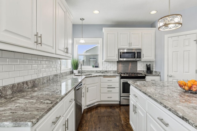 kitchen featuring appliances with stainless steel finishes, white cabinets, and decorative light fixtures