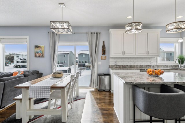 kitchen with white cabinetry, light stone countertops, decorative backsplash, and decorative light fixtures