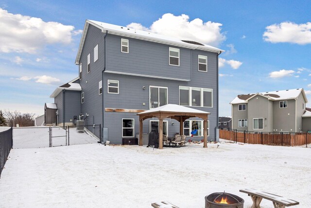 snow covered rear of property with an outdoor fire pit, a gazebo, and cooling unit