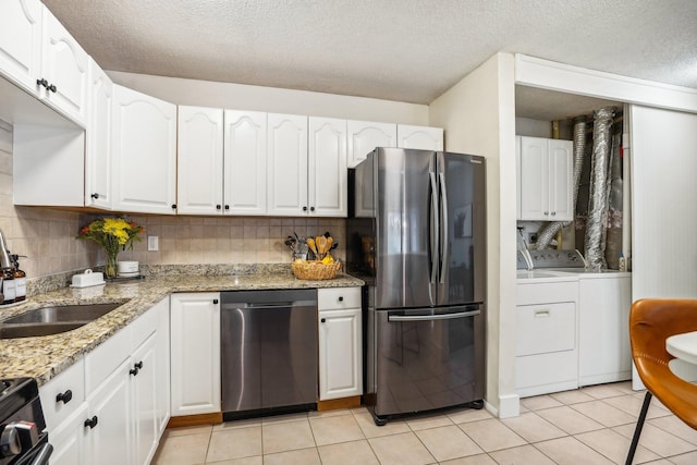 kitchen featuring sink, white cabinetry, stainless steel appliances, light stone countertops, and washer and dryer