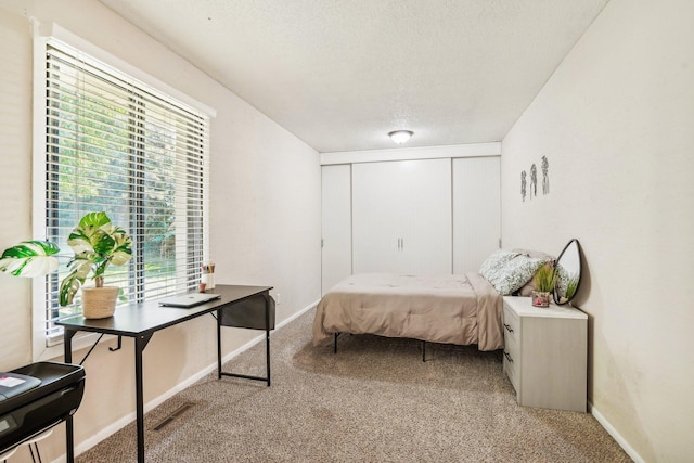 carpeted bedroom with a textured ceiling and a closet