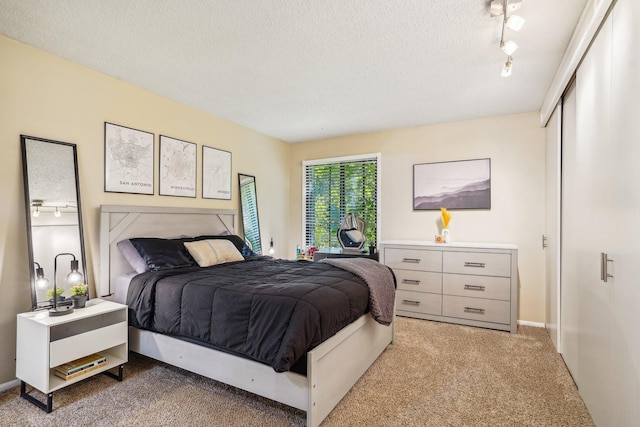 carpeted bedroom with rail lighting and a textured ceiling