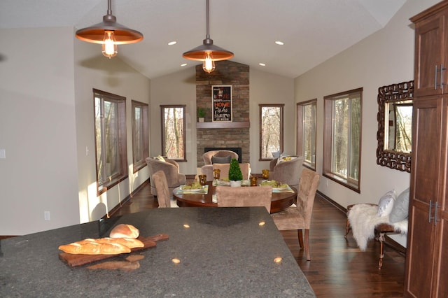 dining space featuring a stone fireplace, dark wood-type flooring, and lofted ceiling