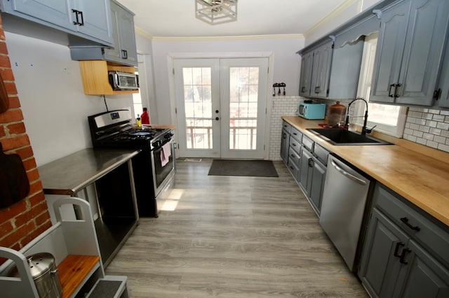 kitchen with crown molding, appliances with stainless steel finishes, sink, and french doors