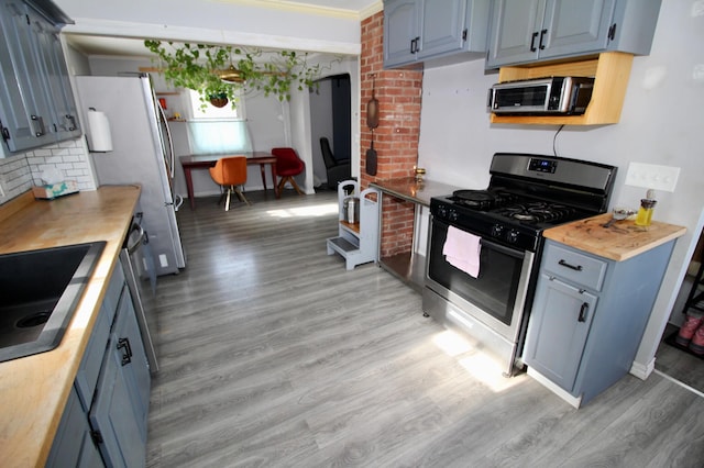 kitchen with tasteful backsplash, sink, light hardwood / wood-style floors, stainless steel appliances, and blue cabinetry